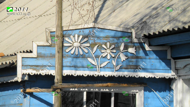 Деревянные накладные украшения в виде цветов над входом в дом 42 на улице Центральной в деревне Вичкино Меленковского района Владимирской области